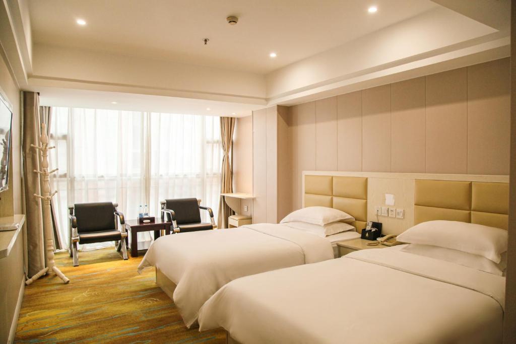 铜仁铜仁世纪大酒店的酒店客房带两张床和一张桌子以及椅子。