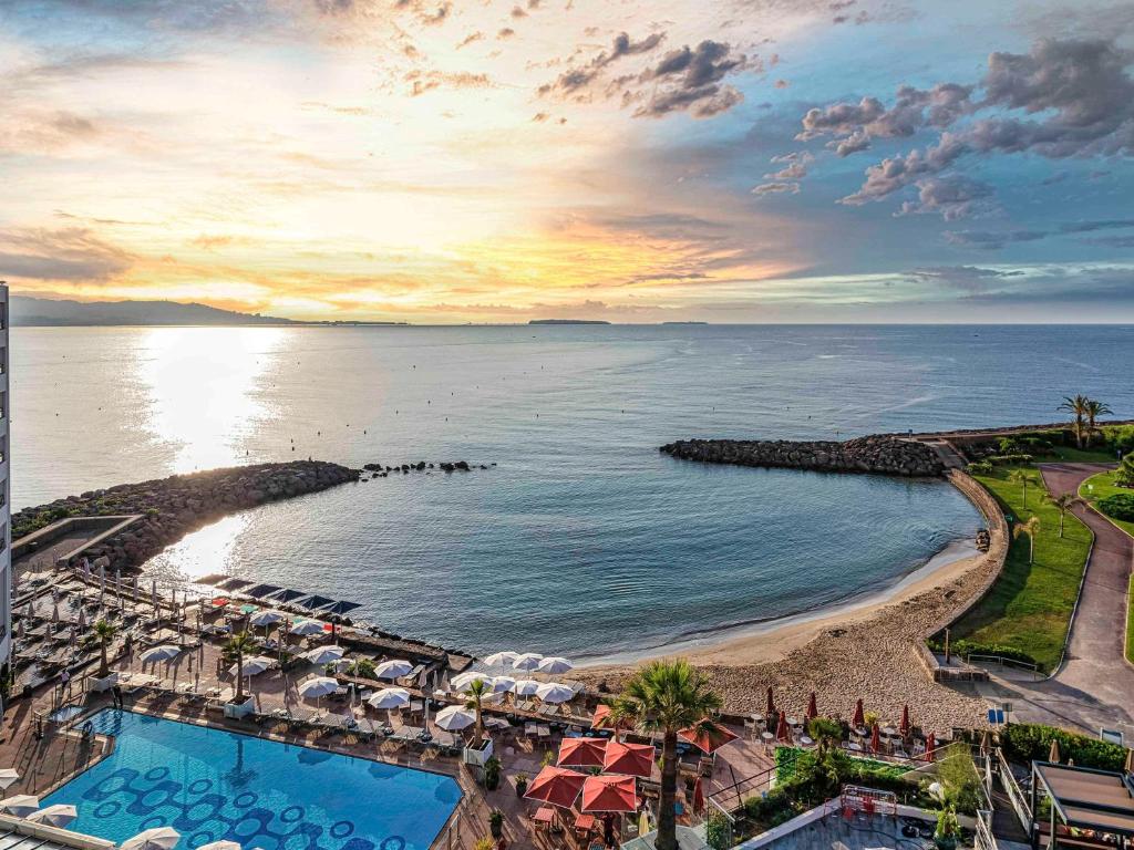 曼德琉-拉纳普勒铂尔曼戛纳曼德里亚皇家赌场酒店的享有带游泳池和海洋的度假村的空中景致