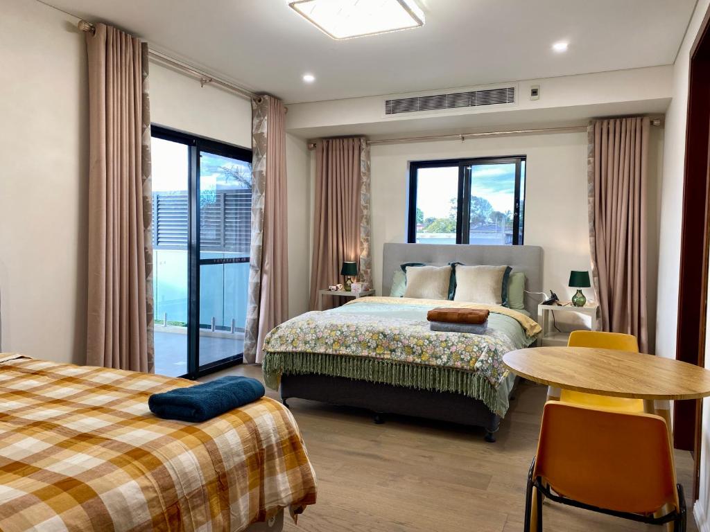 悉尼Penshurst Guest House的一间卧室配有两张床、一张桌子和一张桌子