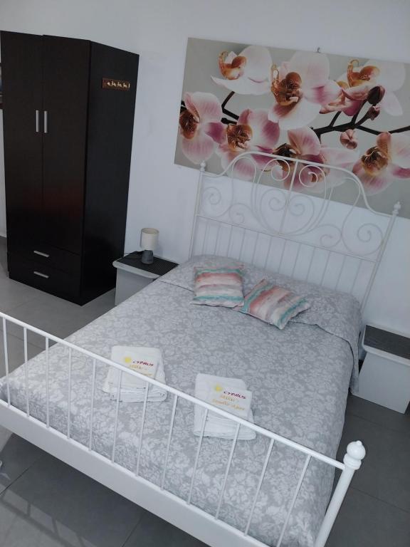 拉纳卡Mikis Studio Type Aprt.的卧室配有白色床,墙上挂着粉红色的鲜花