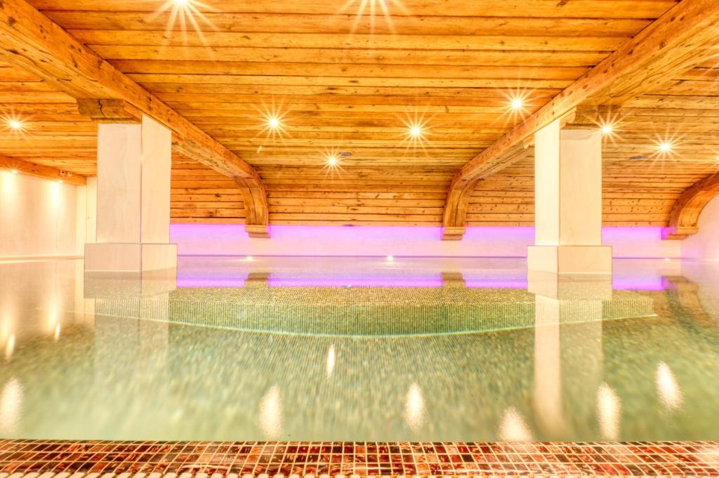 采尔马特Hotel Arca Solebad & Spa的一座带木制天花板的室内游泳池