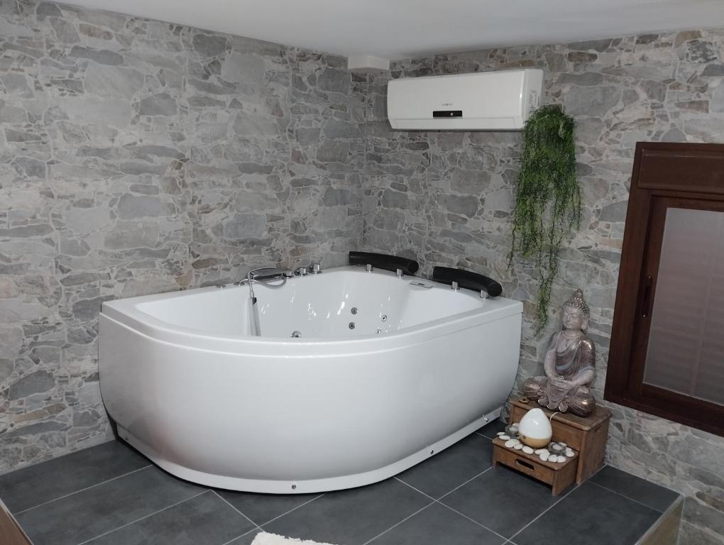 赫雷斯-德拉弗龙特拉Estudio jacuzzi Luz de Jerez的石墙浴室内的白色浴缸