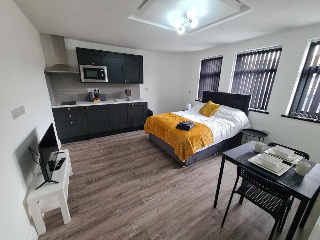 Batley CarrHomestay by BIC Legends 3的一间卧室配有一张床铺和一张桌子,还设有一间厨房