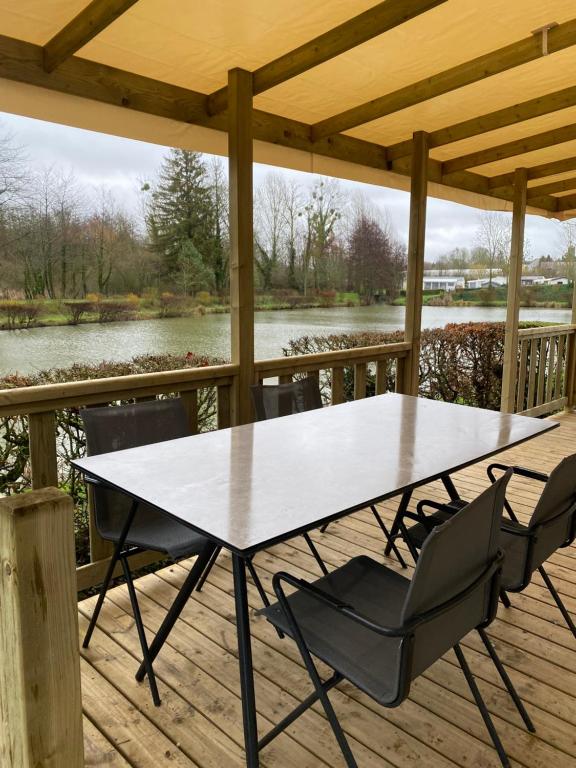 VoyennesMobil-home confort face à l'étang的河景甲板上的桌椅