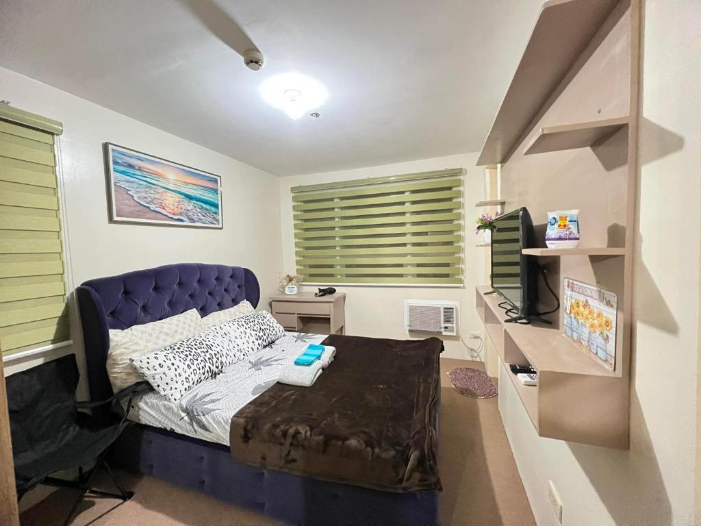 达沃市Jay's Condo - Seawind的一间卧室配有一张蓝色的床和一张书桌及一台电视