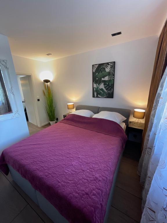 柏林MYSTAY BERLIN Müggelheim的一间卧室配有一张大床和紫色毯子
