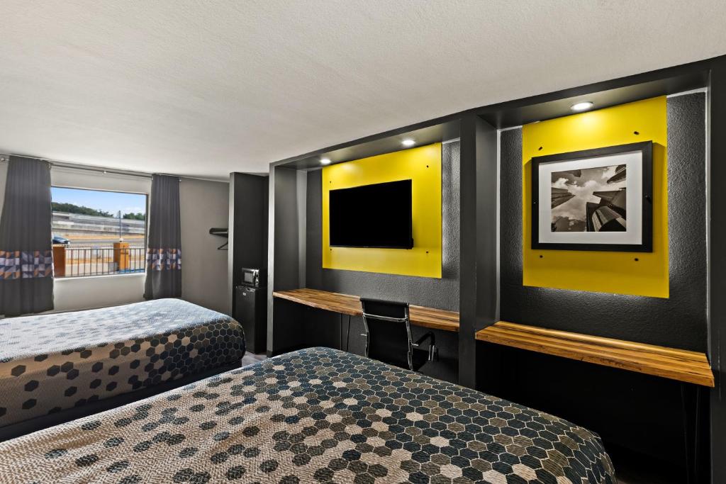 奥斯汀Scottish Inns Austin Downtown的酒店客房设有两张床和一台平面电视。