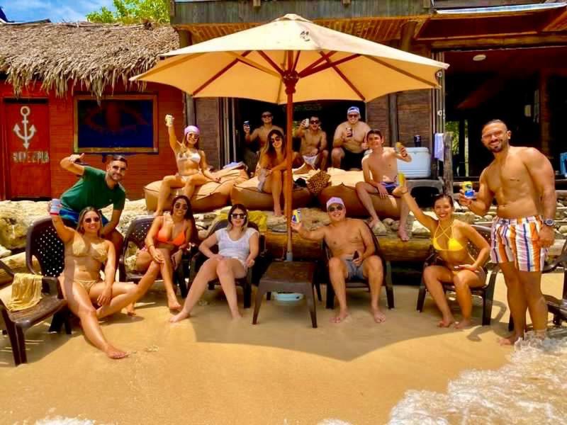 巴尔Hotel Prana Beach的一群人坐在海滩上的伞下