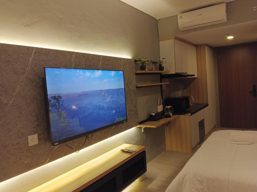 名古屋Free Shuttle Thamrin City Apartments at Nagoya with Netflix & Youtube Premium by MESA的酒店客房的墙上设有大屏幕平面电视。