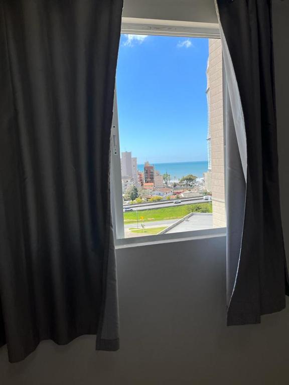 伊塔佩马Apartamento à 380m do Mar的享有城市美景的开放式窗户。
