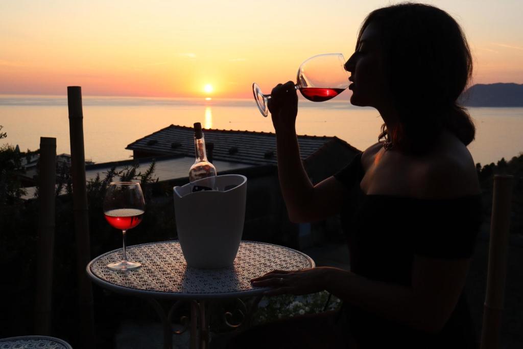 马纳罗拉Sunset Manarola的坐在桌子旁的女人,喝一杯酒