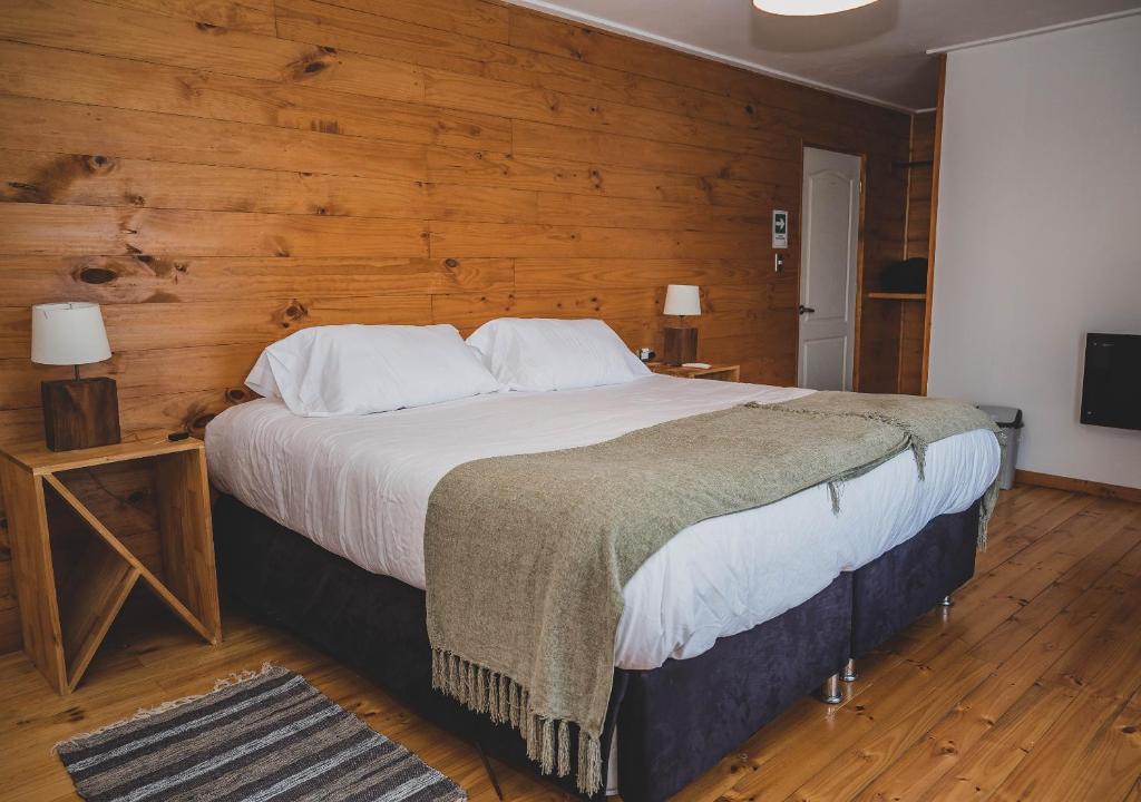 PelluhueHotel Puerto Madera by DOT Boutique的一间卧室设有一张带木墙的大床