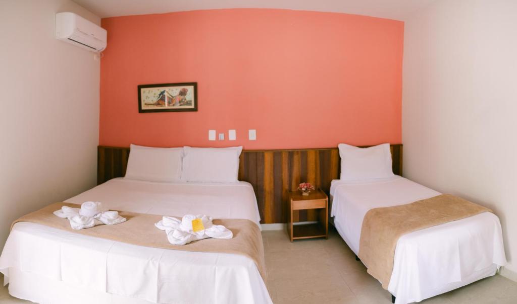 马利西亚斯Hotel Kiribati Maresias的橙色墙壁客房的两张床