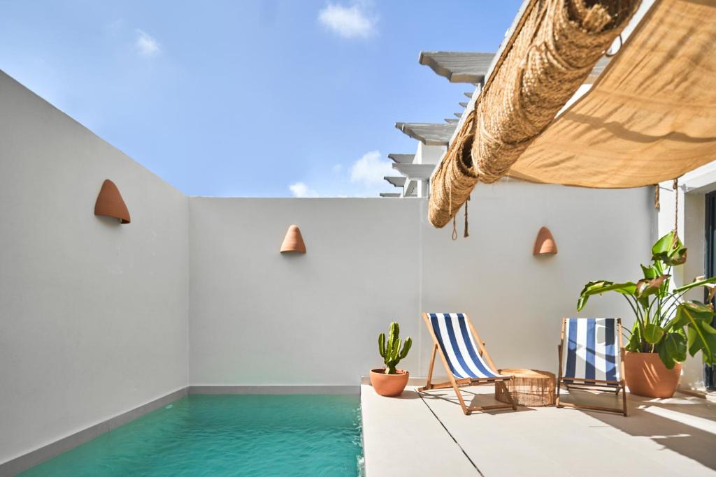 EsteponaEsencia Marbella Casas Boutique的一个带游泳池和椅子的房间