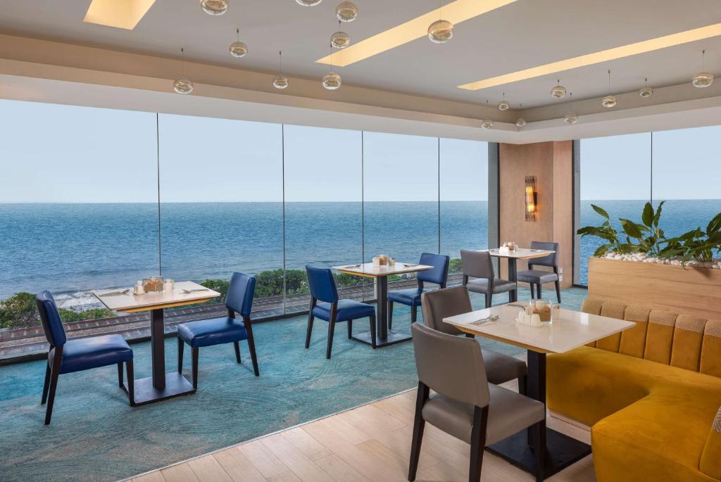 科伦坡Radisson Hotel Colombo的一间有桌椅、可欣赏海景的餐厅