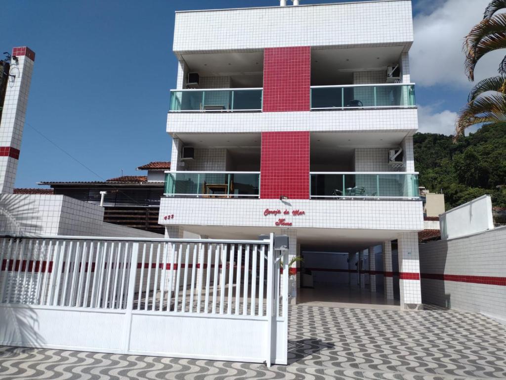 乌巴图巴Apartamento Cereja do Mar的白色的红色建筑,有白色的栅栏