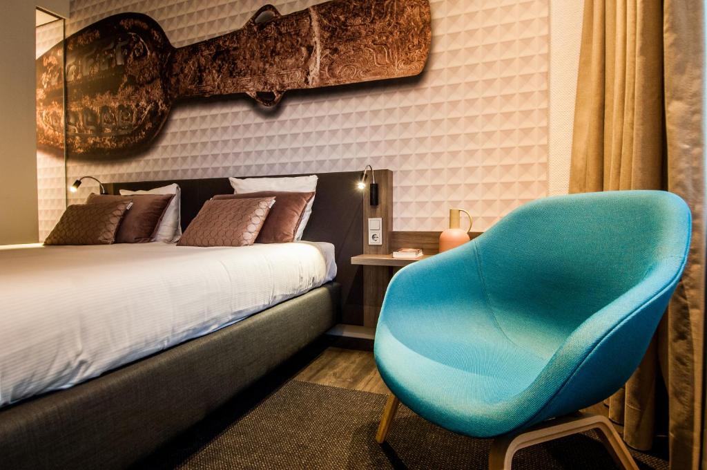 莱顿莱顿金色郁金香中心酒店的卧室配有蓝色椅子,位于床边