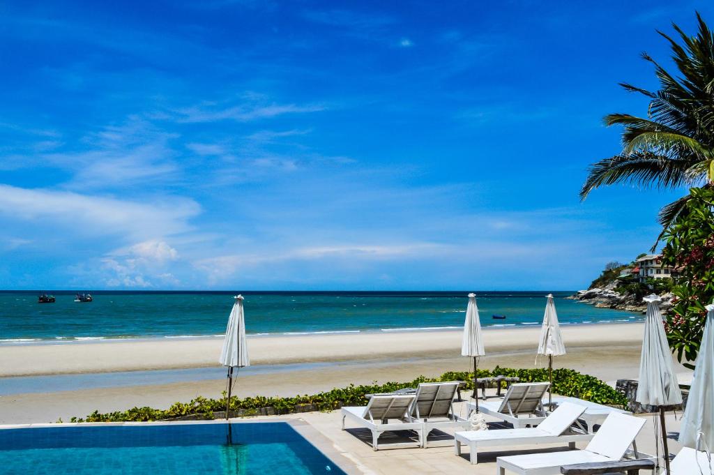 华欣乃恩夏洛特海滨酒店的海滩旁带椅子和遮阳伞的游泳池