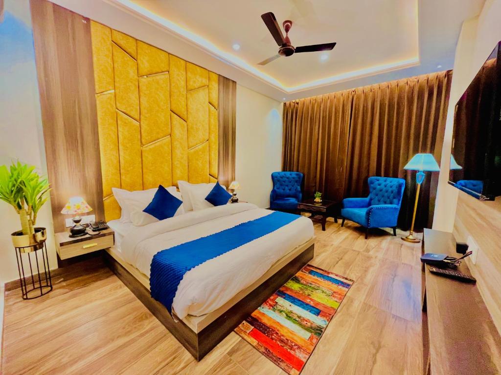 瑞诗凯诗Ganges Blossam, Haridwar-Rishikesh Road - A Four Star Luxury Hotel的一间卧室配有一张特大号床和蓝色的椅子