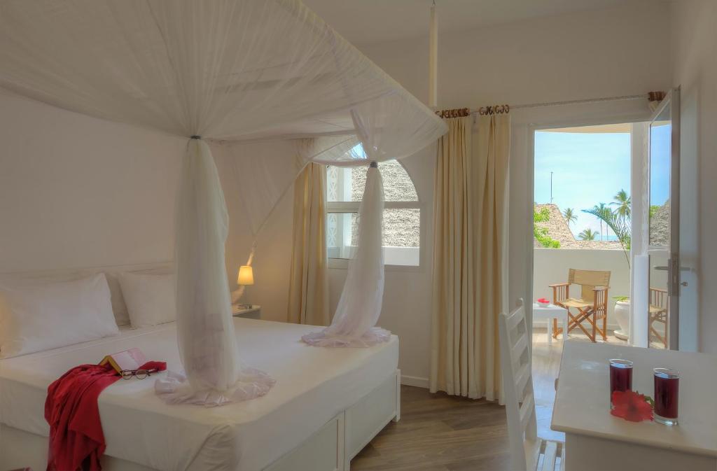 吉汶瓦Diamonds Mapenzi Beach的一间卧室配有一张带天蓬的白色床