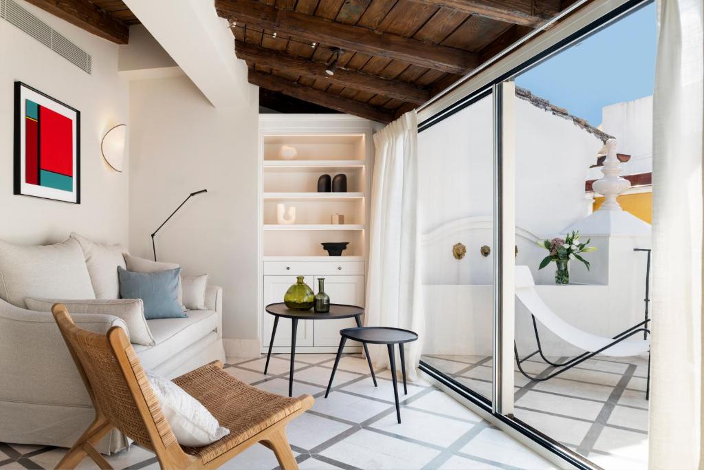 塞维利亚Magno Apartments Casa Pilatos的客厅配有椅子和桌子
