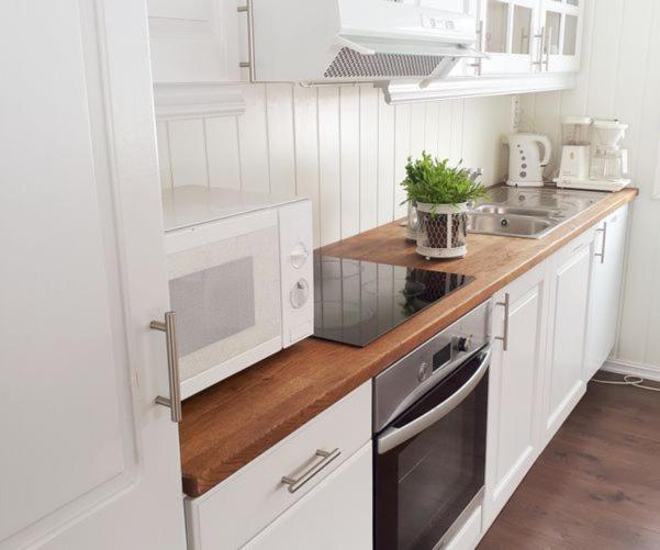 FjellRo的厨房配有白色橱柜和木制台面
