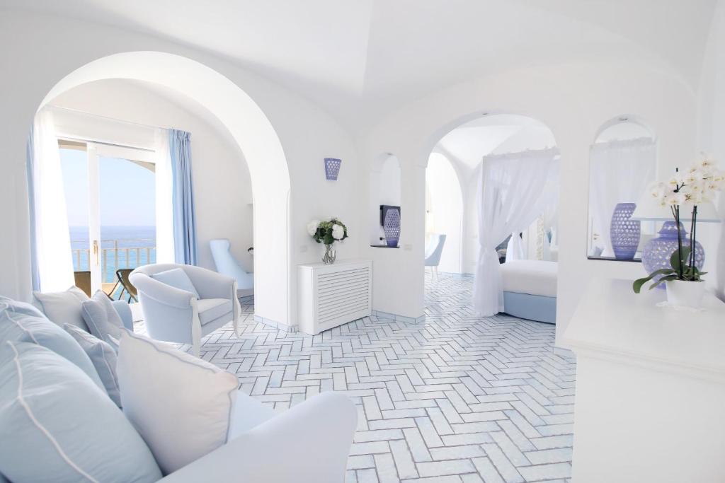 波西塔诺麦润科图酒店的白色的客房配有白色家具,而一间则配有床。