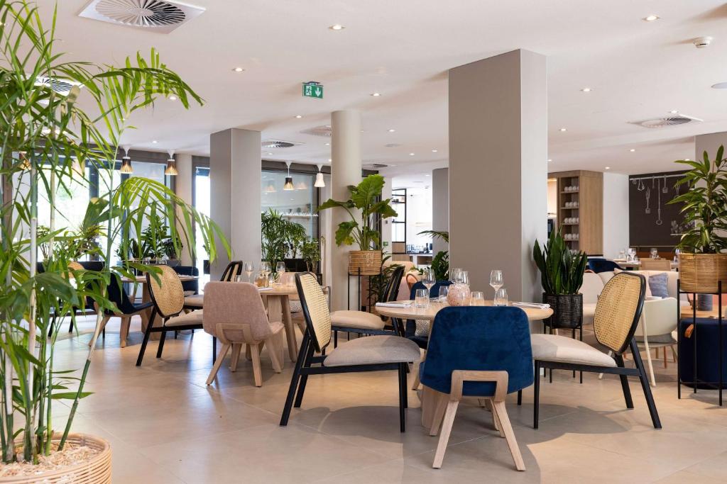 图尔Hilton Garden Inn Tours Centre, France的一间设有桌椅的餐厅,种植了植物