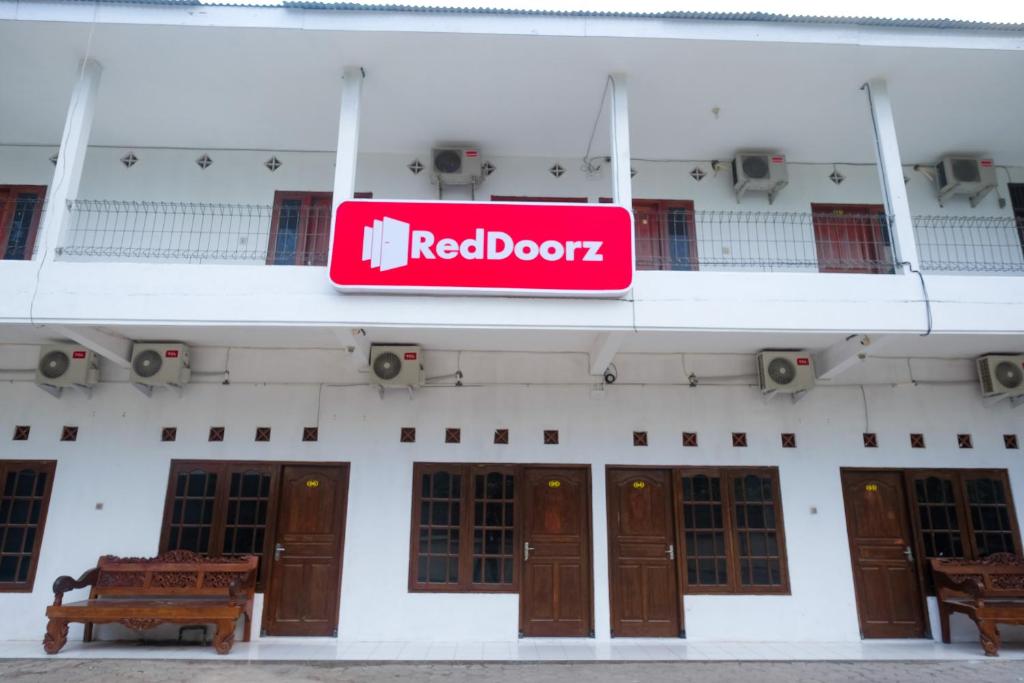 SeturanRedDoorz near Plaza Ambarrukmo Yogyakarta的大楼一侧的红色门标