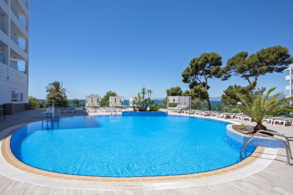 萨洛Hotel Best Punta Dorada的一个带椅子和树木的大型蓝色游泳池
