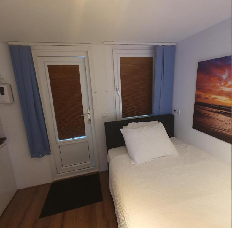 海牙Cozy Garden House kijkduin Beach的一间卧室配有床和2个带蓝色窗帘的窗户。