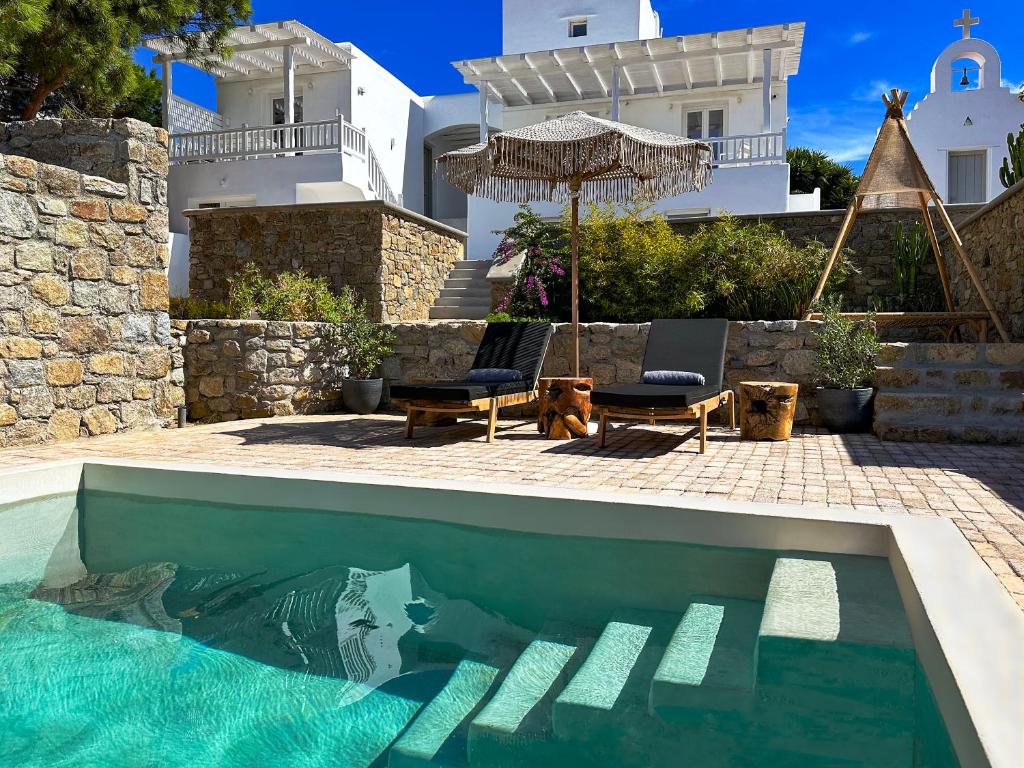 米克诺斯城Sofos Suites Mykonos的一个带两把椅子和一把遮阳伞的游泳池以及一间房屋