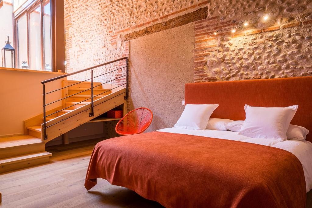 佩皮尼昂马斯拉图尔纳维尔酒店的一间卧室设有一张大床,并有楼梯