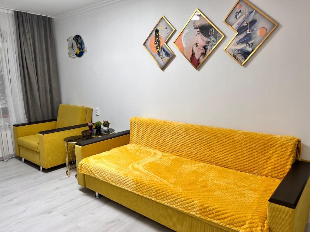 阿拉木图2-х комнатная в центре район ЦУМа的客厅配有黄色沙发和墙上的照片