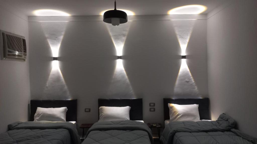 开罗Malak Guest House的墙上灯的房间里设有两张床
