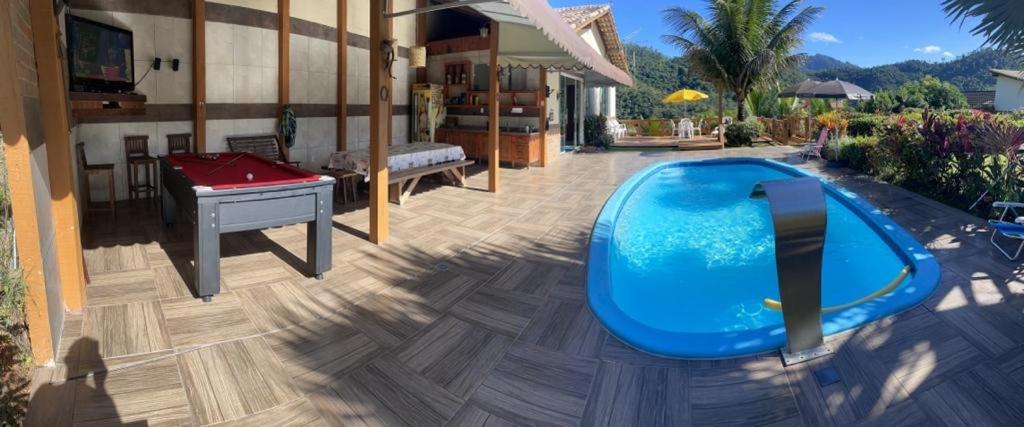 多明戈斯马丁斯Casa nas montanhas com piscina e vista panorâmica的后院设有游泳池和乒乓球桌