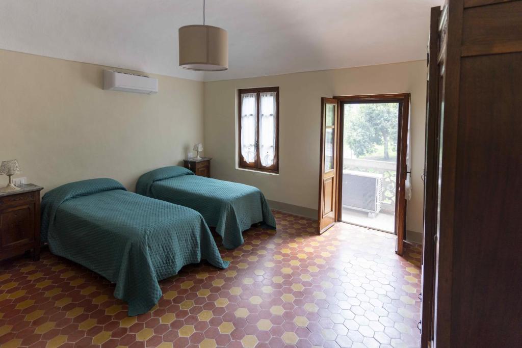 CaminoCountry House La Mela Ruscalla的客房设有两张床和通往阳台的门。