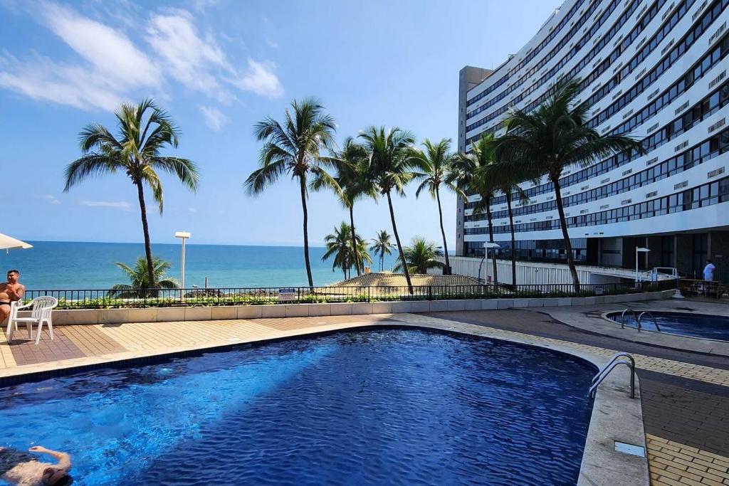萨尔瓦多@ondinaapartreservas Pé na Areia 441的一座棕榈树游泳池和一座建筑