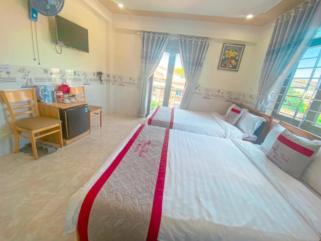惹岛KHÁCH SẠN HƯNG THỊNH - Lý Sơn的一间卧室配有一张大床、一张书桌和窗户。