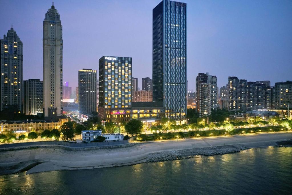 武汉武汉富力威斯汀酒店的城市天际线,夜晚有河流和建筑
