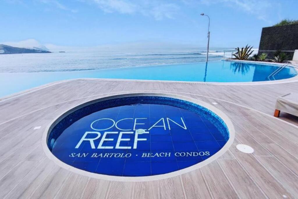 圣巴托洛Departamento de Playa San Bartolo Ocean Reef - SOL, ARENA Y MAR的游泳池旁的海洋珊瑚礁读物标志