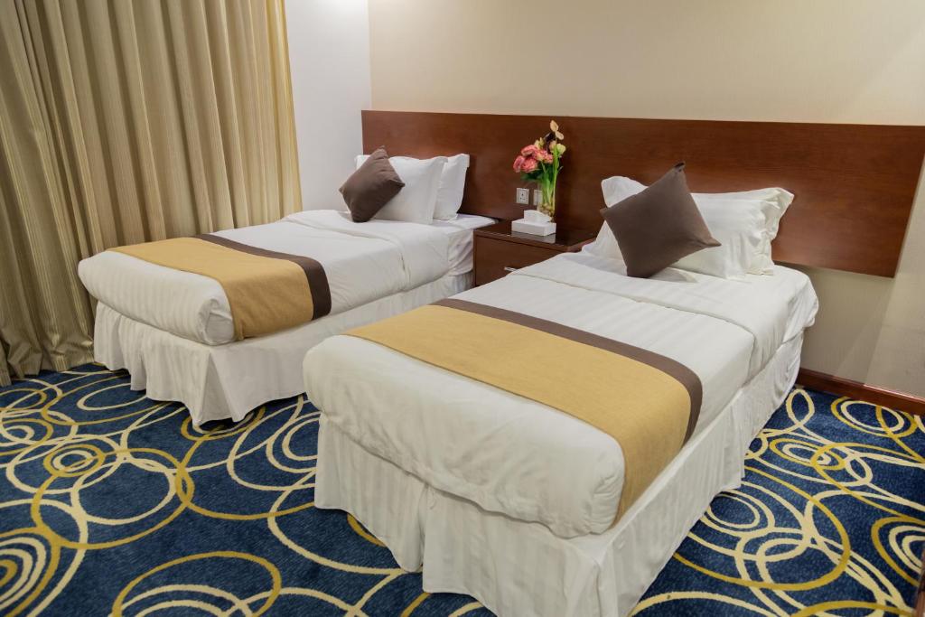 吉达Carawan Hotel Jeddah的鲜花酒店客房内的两张床