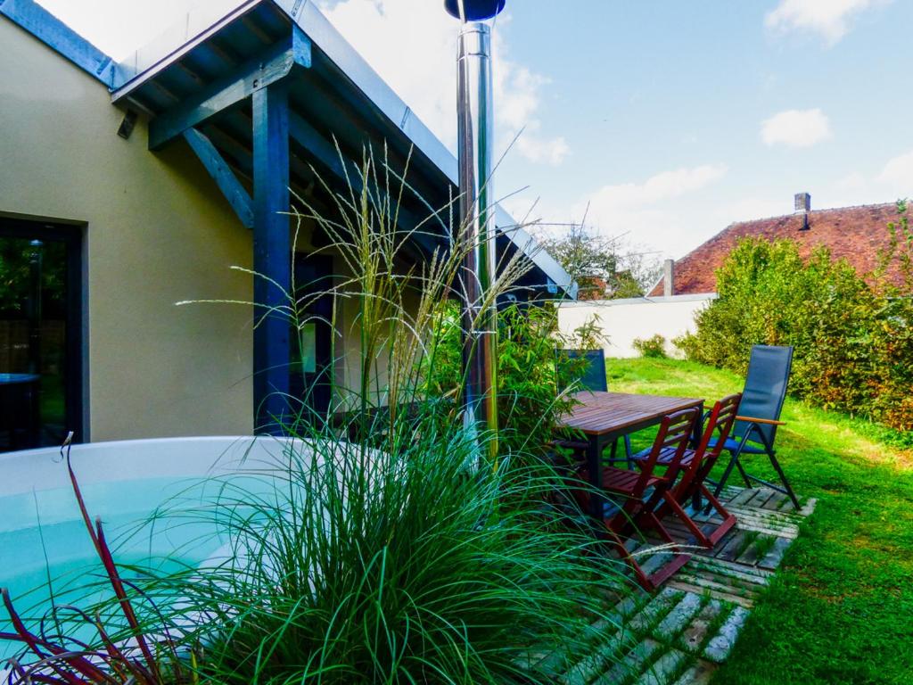梅斯尼圣佩尔Maison chaleureuse avec son bain enchanté !的一个带桌椅的庭院和一个游泳池