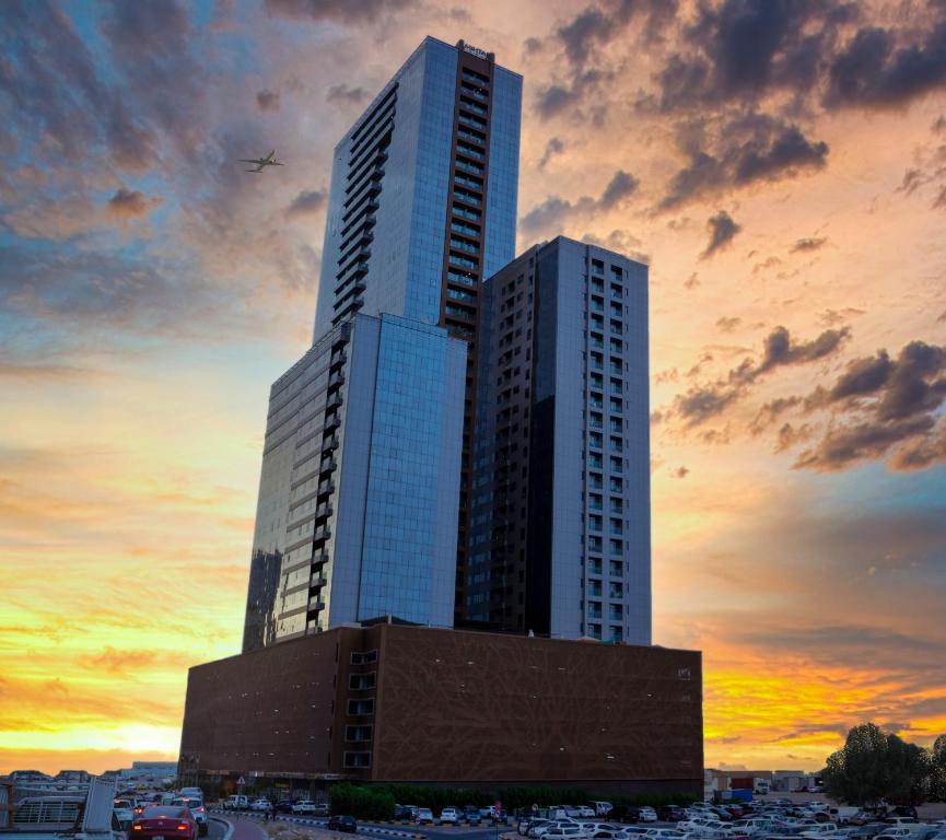 沙迦Luxe Grand Hotel Apartments的一座高大的建筑,背面有日落