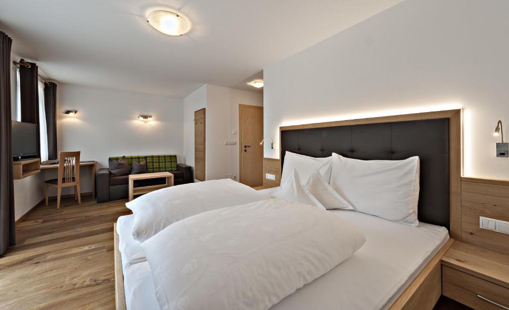 圣马蒂诺Hotel Pfandleralm的一间带白色大床的卧室和一间客厅