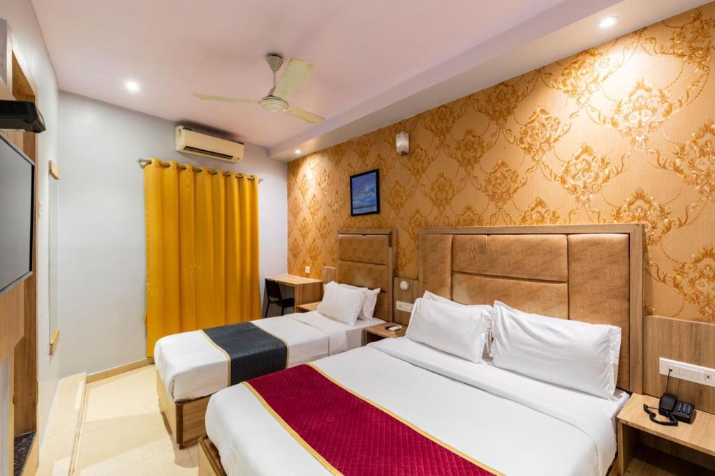 孟买LOTUS GRAND HOTEL MUMBAI的酒店客房带两张床和黄色窗帘