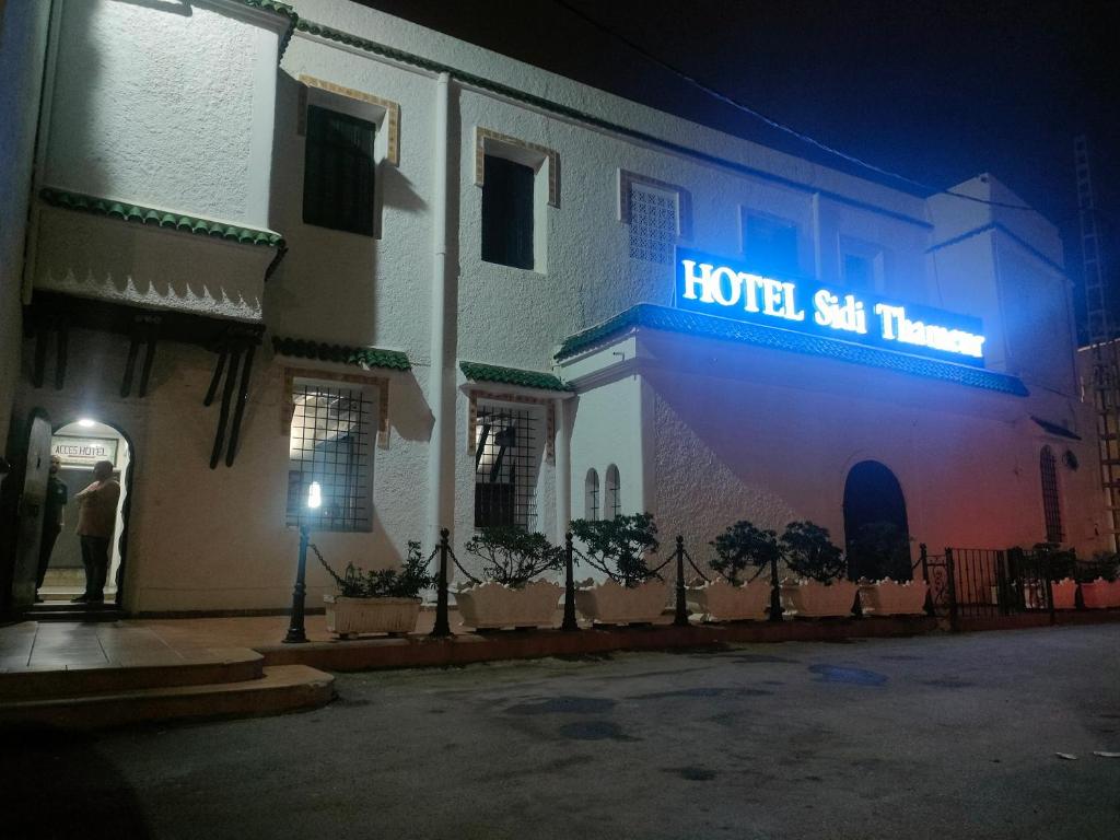 阿尔及尔HOTEL SIDI THAMEUR Alger的夜间大楼一侧的酒店标志