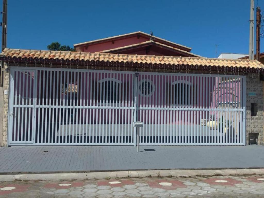 佩鲁伊比Casa Rosa de Peruíbe - Casa de Temporada 3 dormitórios, 10 hóspedes, piscina, wi-fi, netflix, 800 metros da praia的房屋前的白色围栏
