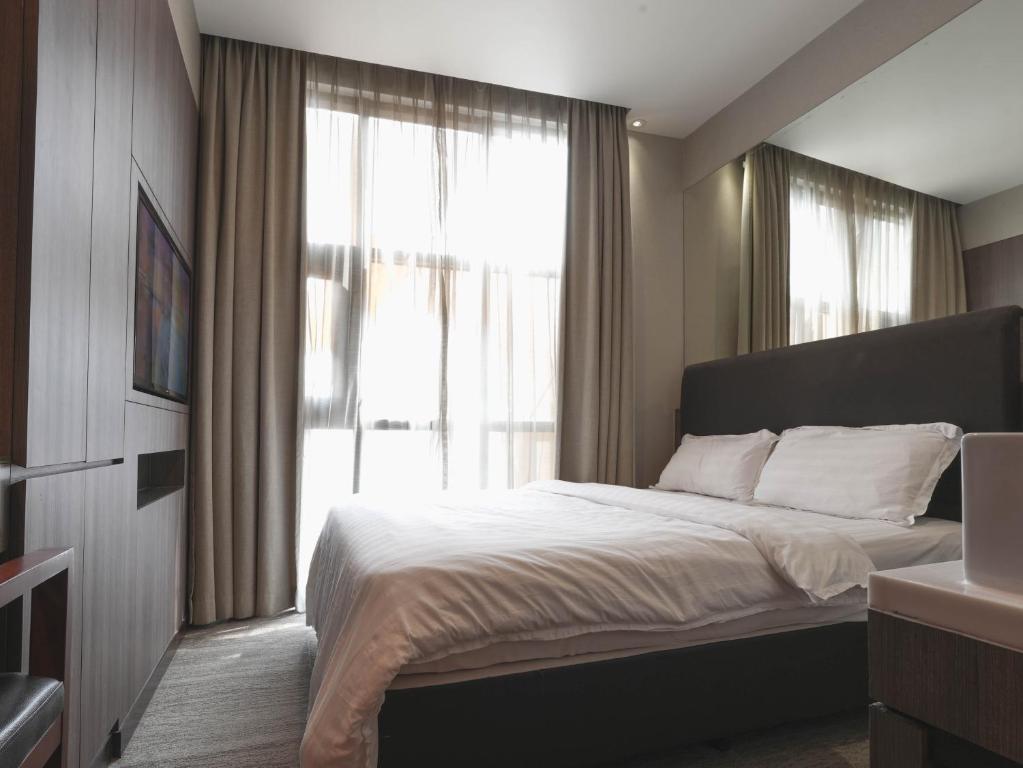 新加坡Amrise Hotel Kitchener, Check In 9PM, Check Out 8AM的一间卧室设有一张床和一个大窗户