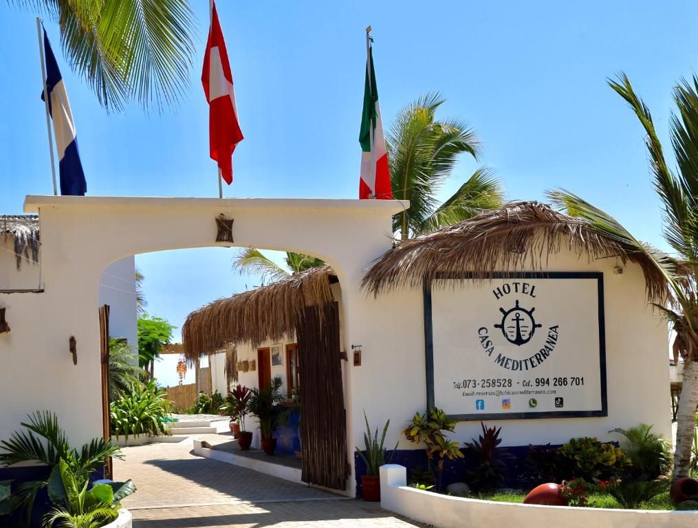 曼克拉Hotel Casa Mediterranea Mancora的上面有两面旗帜的建筑